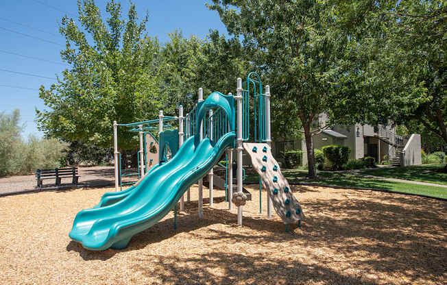 A green slide in a playground surrounded by trees at Autumn Oaks Apartments, Roseville, CA, 95678