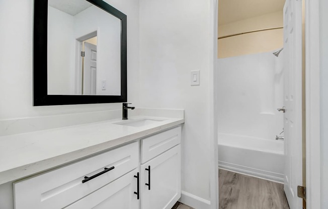 A bathroom with a white vanity and a mirror.