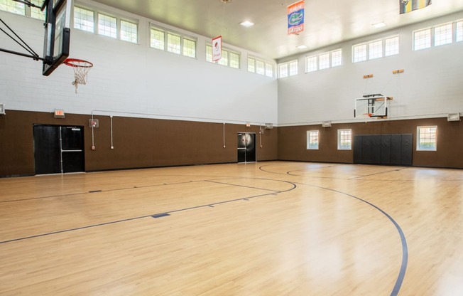 the inside of a gym with a basketball court and wood floors