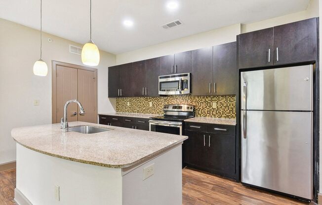 a kitchen with stainless steel appliances and a marble counter top at Lakeline East Apartments, Texas