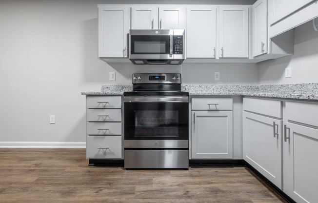 a kitchen with white cabinets and a stove and microwave