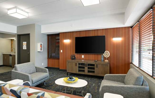 A modern lounge area with a television, chairs, and a coffee table.