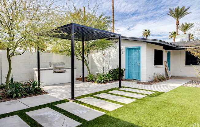 a small white house with a blue door and a yard with a stone walkway