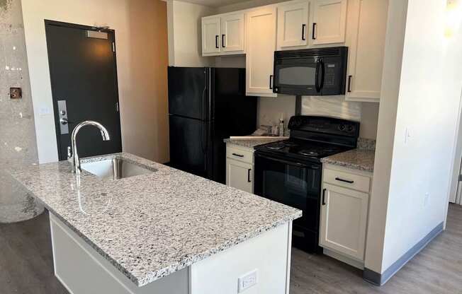 A kitchen with black appliances and granite countertops.