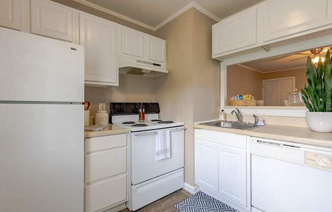 A white refrigerator is in a kitchen with white cabinets.