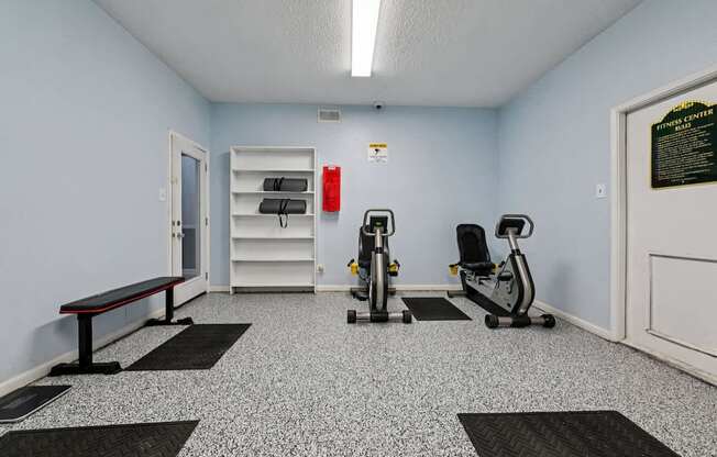 A gym with a bench, weights, and exercise equipment.