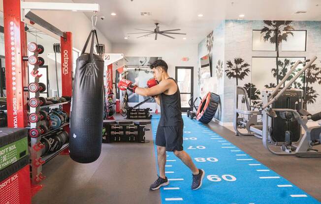 A man is boxing in a gym with a punching bag.