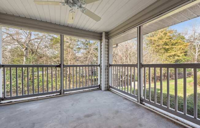 A patio with a white ceiling fan and a view of a grassy area.