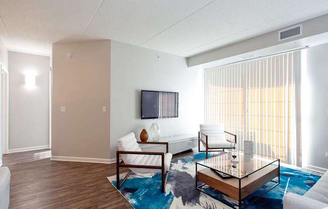 A living room with a white couch, a wooden coffee table, and a flat screen TV mounted on the wall.