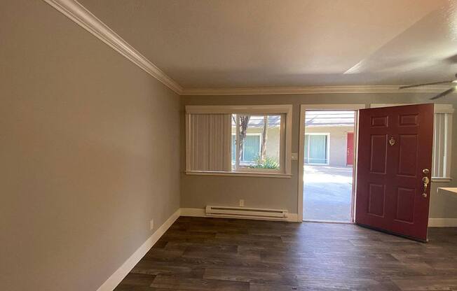 A room with a red door and a window with blinds.