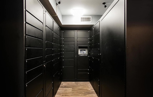 A long hallway with black lockers and wood floors.