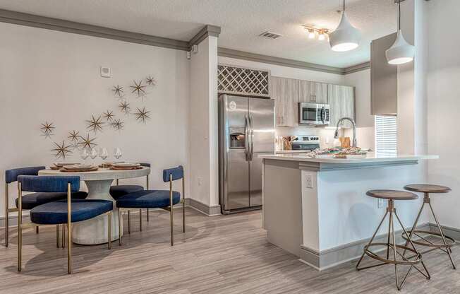 A kitchen with a table and chairs in front of a refrigerator.