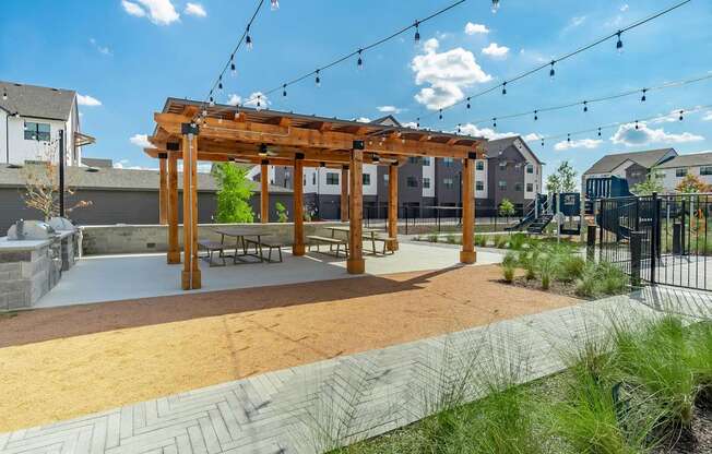a pergola sits in the middle of a park with a playground in the background