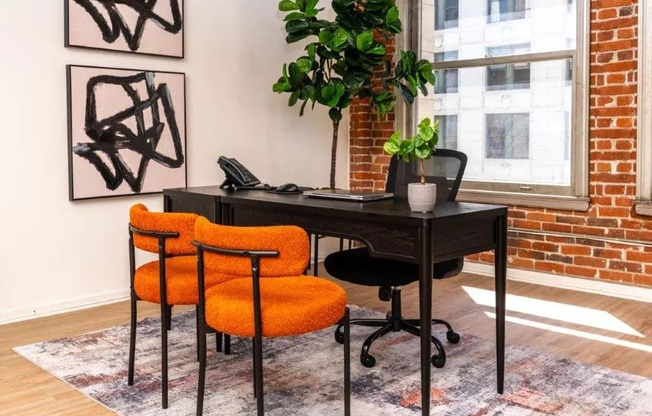 desk with two orange chairs against a brick wall