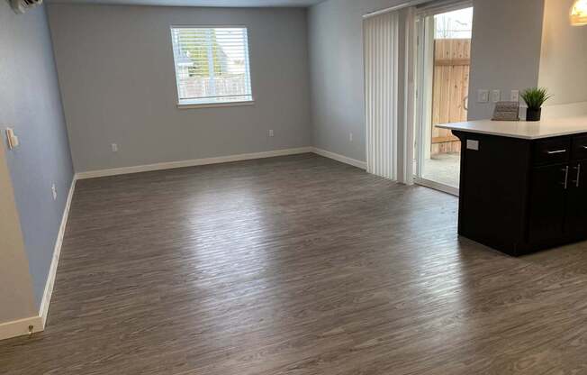 A room with a wooden floor and a window with blinds.
