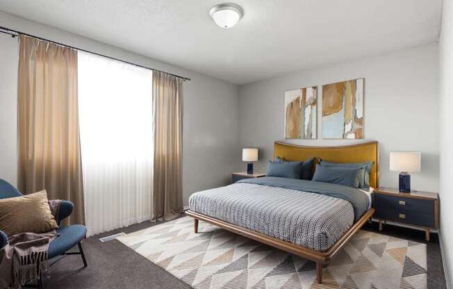 Element at 4411 Macon Apartments A bedroom with a bed, chair, and two lamps.