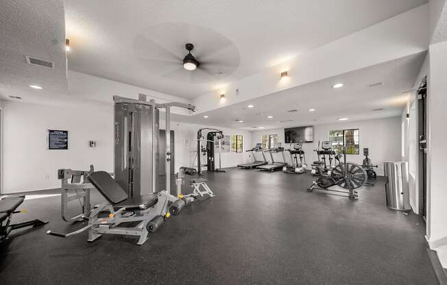 A spacious gym with a variety of equipment including treadmills, stationary bikes, and weight machines.