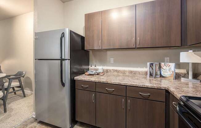A kitchen with a refrigerator, cabinets, and a countertop.