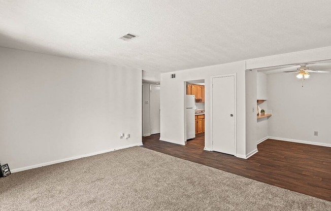 an empty living room with wood flooring and white walls