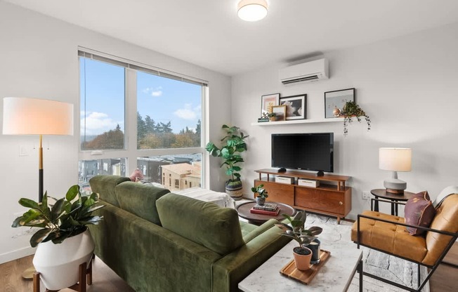 A living room with a green couch, a television, and a fireplace.