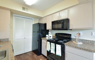 a kitchen with white cabinets and black appliances