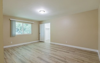 an empty living room with wood floors and a window