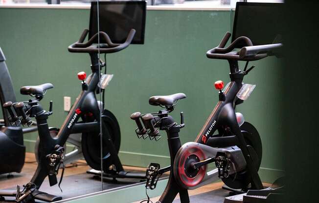 a row of exercise bikes in a room with a green wall