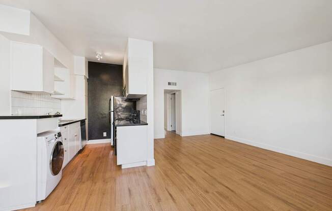 A kitchen with white cabinets and a wooden floor.