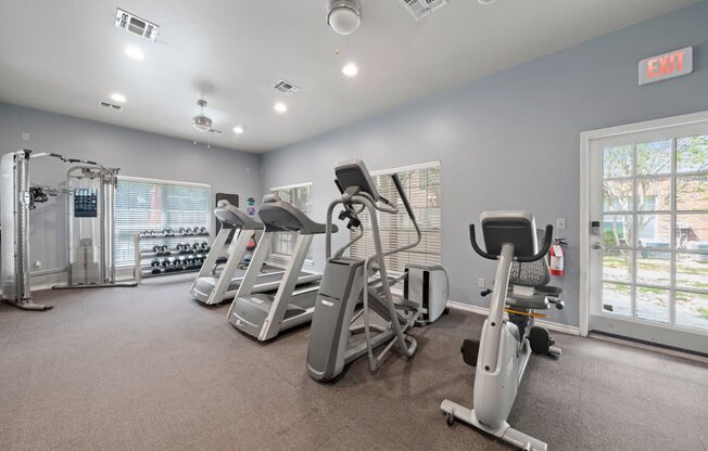 the gym has plenty of cardio equipment and a large window