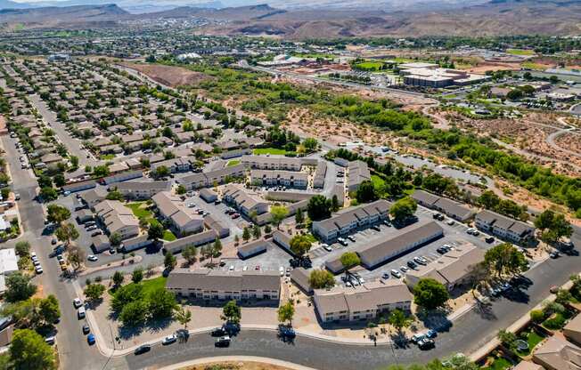 an aerial view of a city with houses and cars in a parking lot