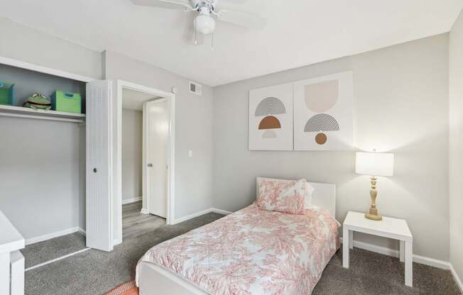 A bedroom with a bed, nightstand, and a ceiling fan.