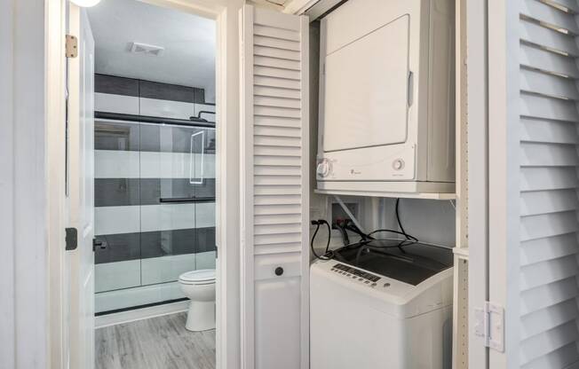 Fusion Warner Center apartments in Woodland Hills in-unit laundry with top load washer and front load dryer in closet with shutter doors.