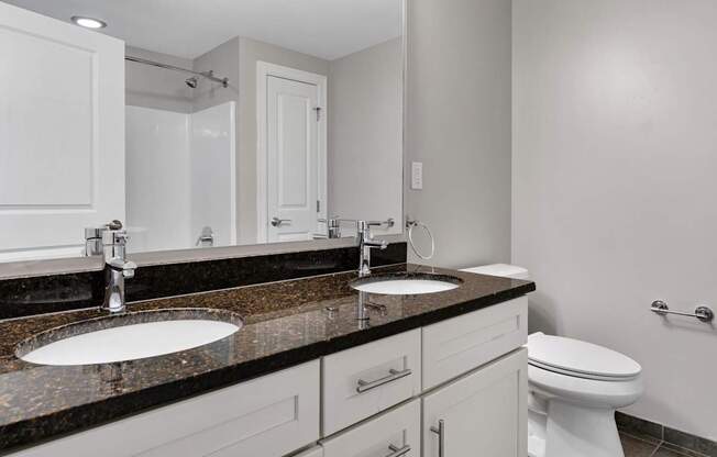 A bathroom with a sink, toilet, and mirror.