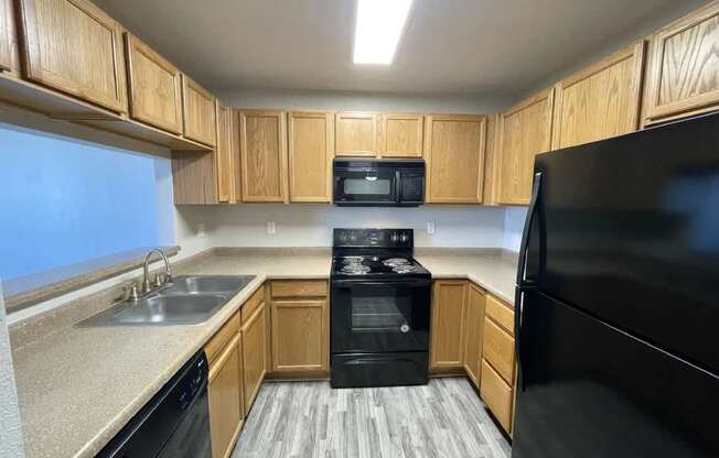 A kitchen with black appliances and wooden cabinets.