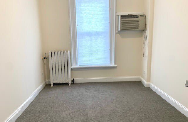 an empty room with a radiator and a window