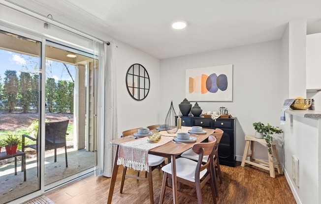 A dining room with a table set for two and a view of the backyard.