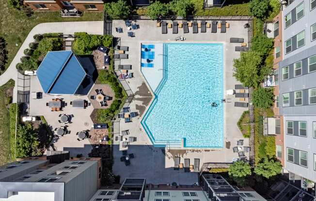 an aerial view of a large swimming pool surrounded by buildings and trees