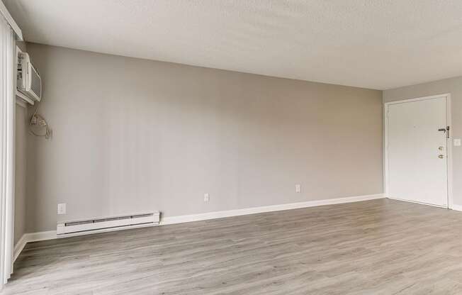 an empty living room with wood floors and white walls