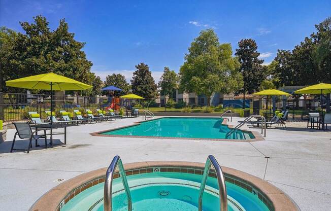 a swimming pool with yellow umbrellas and chairs around it and a blue pool