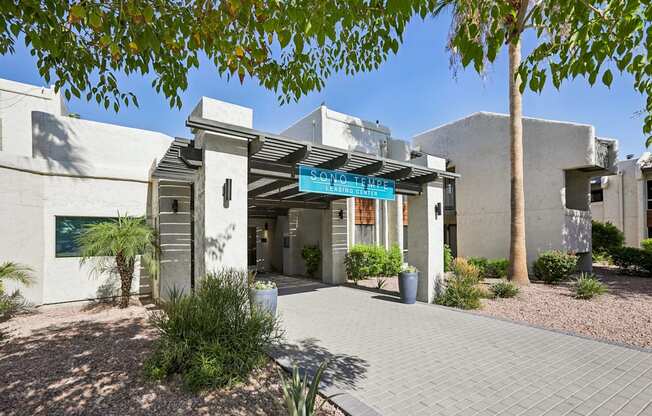 A building with a blue awning is surrounded by plants and trees.