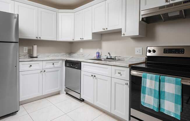 a kitchen with white cabinets and black and silver appliances at Fairways of Inverrary, Lauderhill, FL