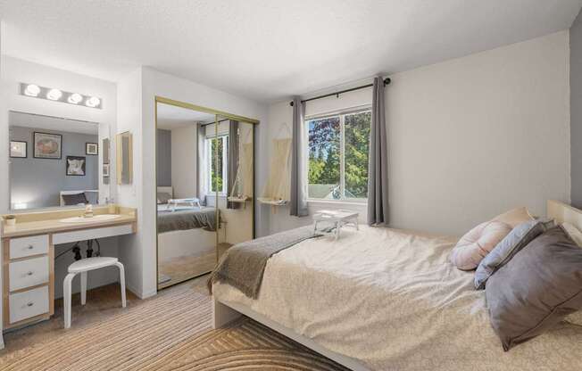 A bedroom with a bed, vanity, and chair at Clackamas Trails Apartments, Oregon, 97222