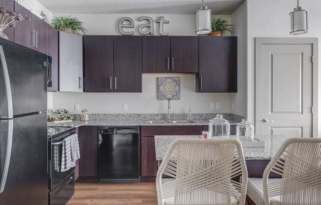 a kitchen with black appliances and a table with chairs