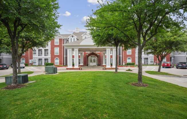 a large building with a lawn and trees in front of it