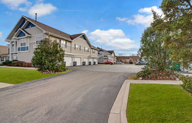 A well-maintained exterior here at Arbor Ridge featuring attached garages, clean paved drive, and lush green landscaping. Bright siding and mature trees create a welcoming, attractive residential setting.