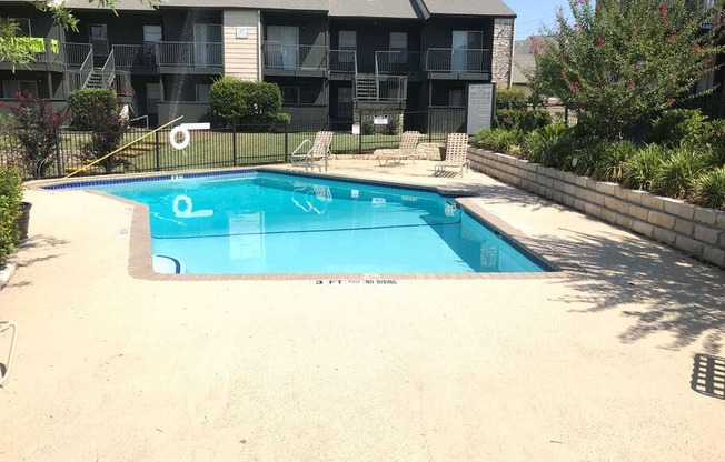A small pool in a backyard with a building in the background.