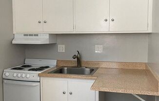 a kitchen with white cabinets and a stove and sink