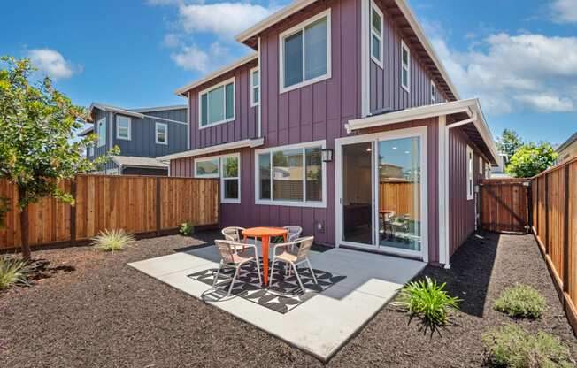 a patio with a table and chairs in front of a house