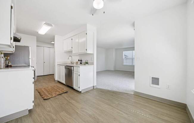 A kitchen with white cabinets and a wooden floor.