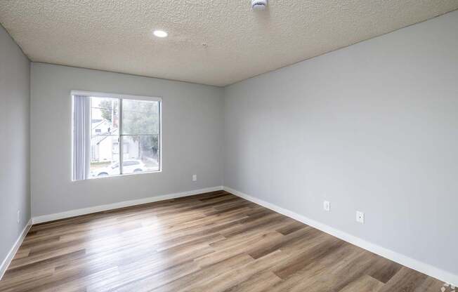 A room with wooden flooring and a window.